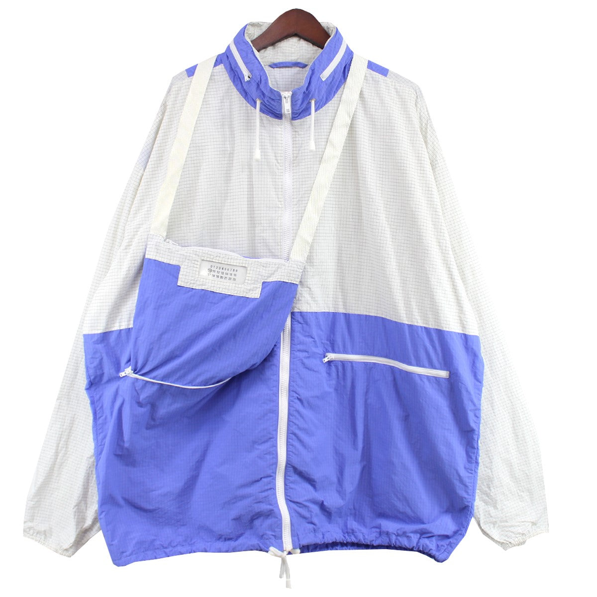 Maison Margiela（メゾンマルジェラ） MAISON MARGIELA メゾンマルジェラの19SS RIPSTOP HOODED BLOUSON リップストップ フーデッド ロゴ 四つタグ 四つ糸 バッグ ドッキング ブルゾン オーバーサイズ カレンダー ジャケットです。ポップなカラーが目を引くナイロンフーデッドブルゾンです。 同素材のサコッシュが一体化となっております。 サコッシュは右ポケットの内側と繋がっており収納する事も可能です。 碁盤の目状に編みこまれたナイロンのリップストップ地が使用されております。 中古市場でも滅多にでない非常にオススメの１点です。 古着・中古 アイテム